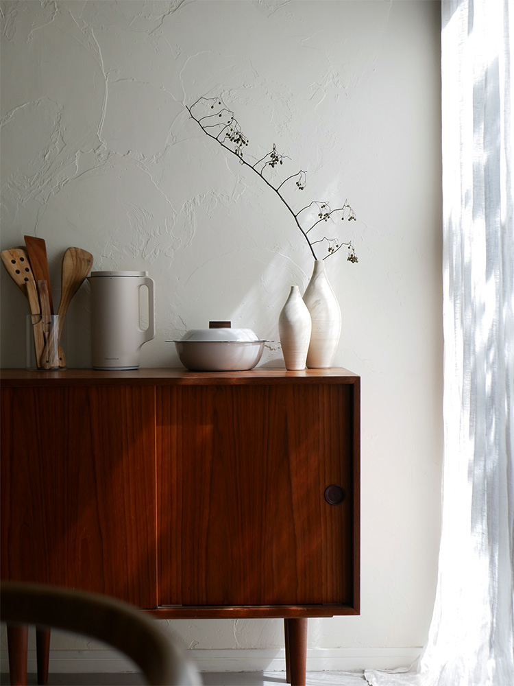 インテリアルーム内にKINTOの琺瑯×天然木のIH卓上鍋が置かれ、家具や絵画、観葉植物で装飾されている様子