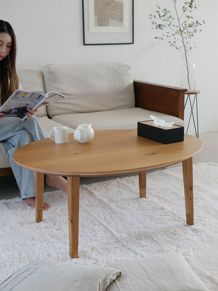 オーク材を使用した高さ調節可能なリビングこたつが、フローリングのリビングルームに設置されています