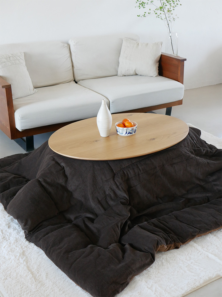 高さ調節可能なリビングこたつとクッションが並ぶ木製フローリングのナチュラルなリビングルーム