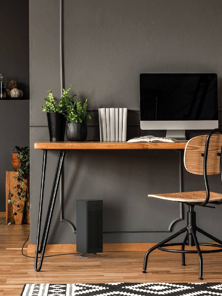 スタドラフォームのAnna bigファンヒーターが木製のデスクと椅子が配置されたインテリアルームに設置されている様子