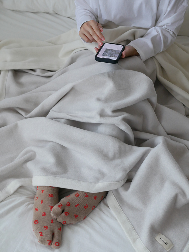 ココマニのオーガニックコットン製シングルサイズ毛布が敷かれた整ったベッド