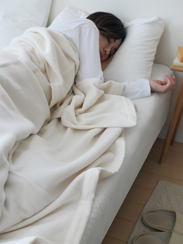 ココマニのオーガニックコットン製シングルサイズ毛布が敷かれた快適なベッド