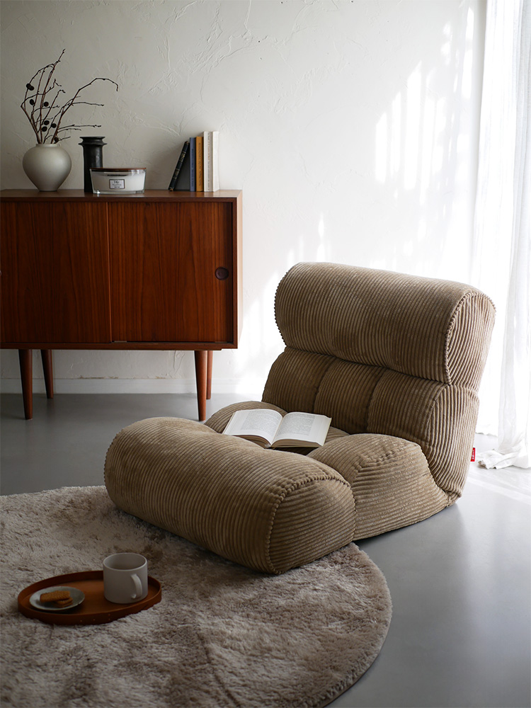 木製フロアのリビングルームに置かれたピグレットの茶色いソファー座椅子