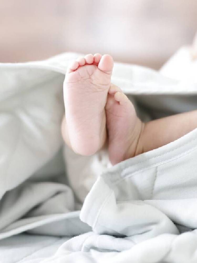 オーガニックコットン100％のシングルサイズ布団カバーが整えられたベッドと裸足の子供