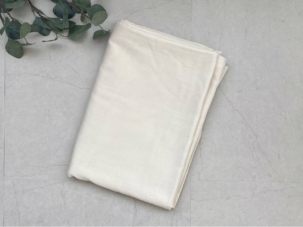 オーガニックコットン100％の白い布団カバーがテーブルに整然と敷かれている様子