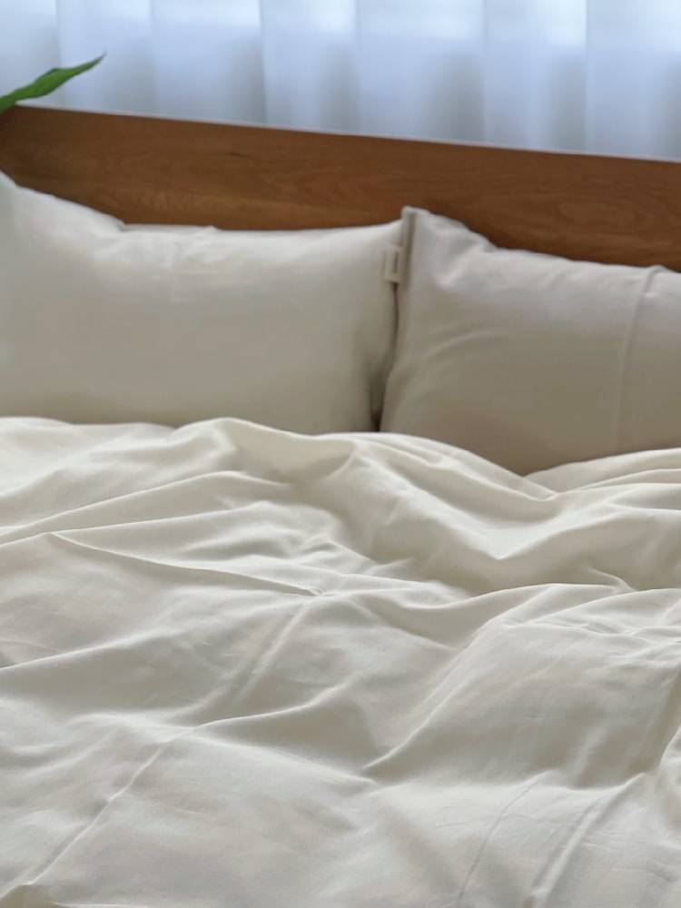 シングルサイズのベッドにオーガニックコットン100％のココマニ布団カバーと枕が整えられた画像