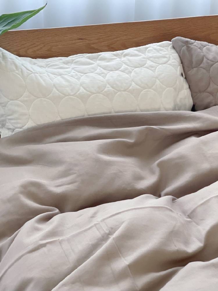 オーガニックコットン100％のシングルサイズ布団カバーをかけた整えられたベッドが配置された寝室