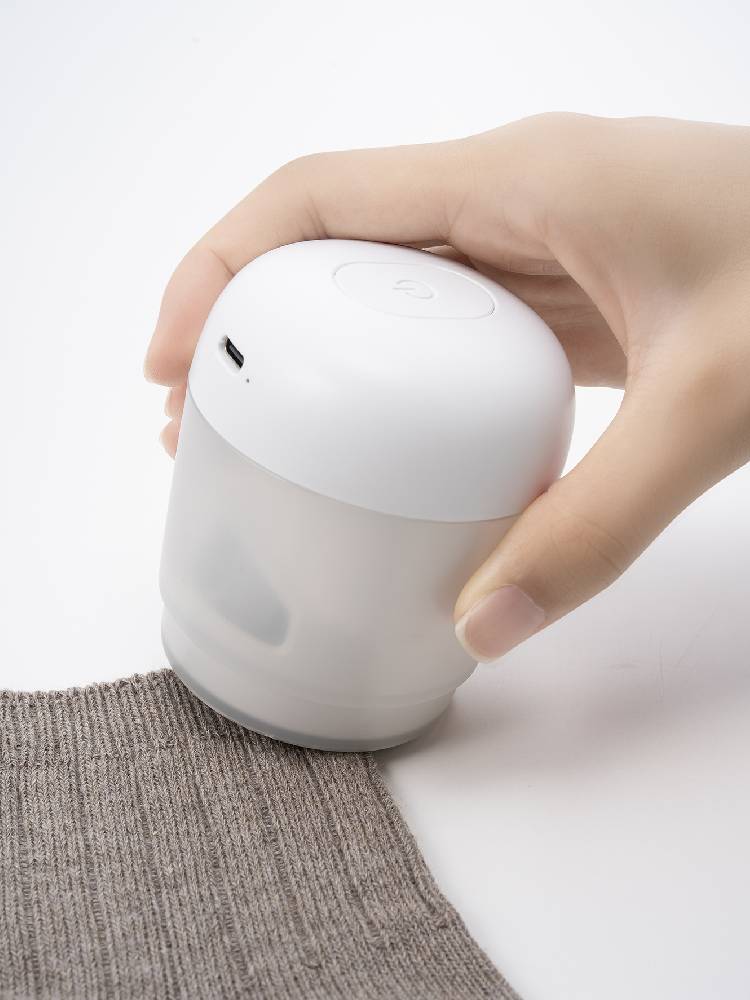 プラスマイナスゼロ毛玉クリーナー本体（白）、USBケーブル、クリーニングブラシ、取扱説明書が並べられている様子