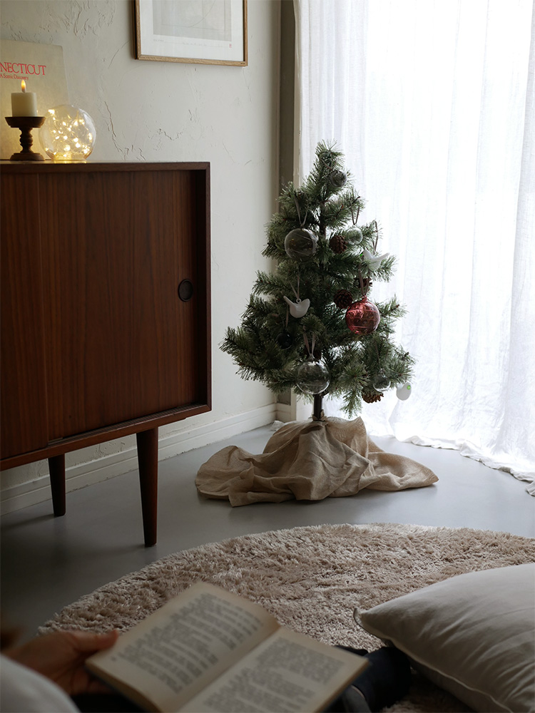 クリスマスツリーに飾られたイッタラの無鉛ガラスオーナメントセットとスタイリッシュなインテリア照明が調和したリビングルーム