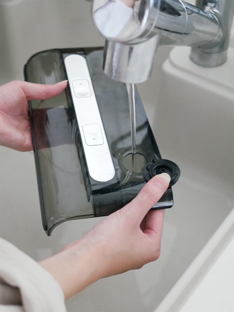 キッチンのシンクと蛇口の近くで使用されているMindoo AquaX掃除機の画像