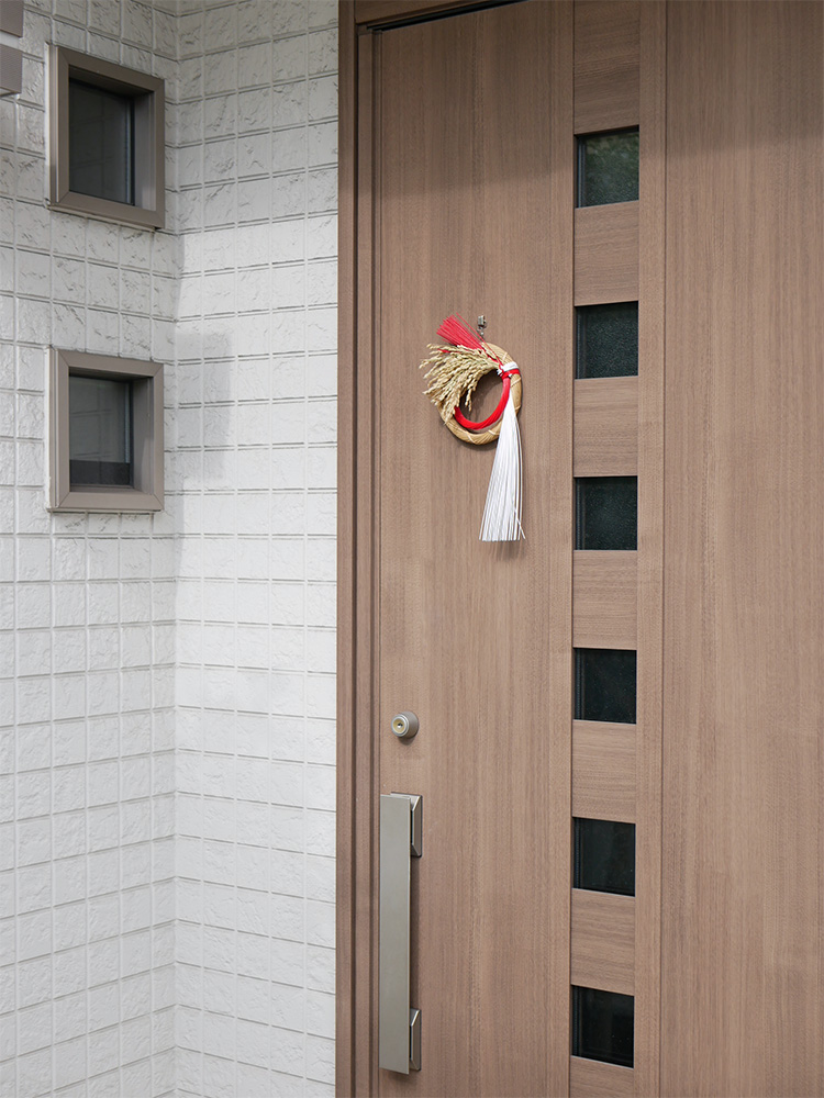 竹や稲の迎春ことほぎリースが木製のドアに掛けられている