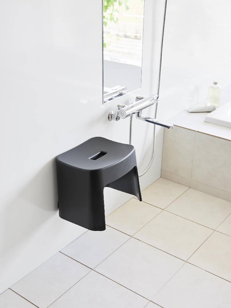 銀色のプラスチック製マグネット風呂イスが木製床と配管器具のある浴室に設置されている様子