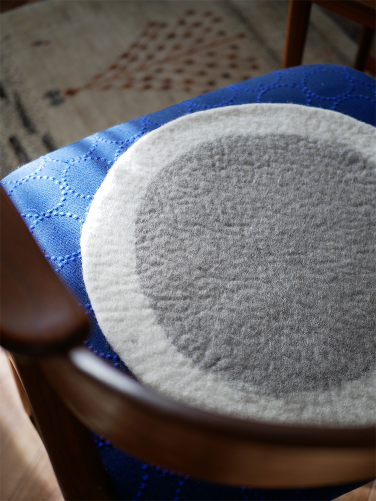 ブルーのニュージーランドウール100％製ウールフェルトチェアシートが、木目調のハードウッドフローリング上に敷かれている様子