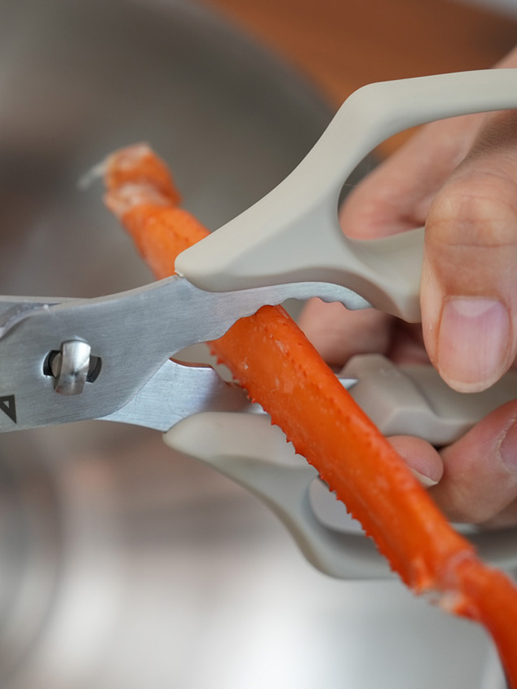 協和工業のムテキバサミを使って人参を切る手元とキッチン用品が並ぶキッチンの様子