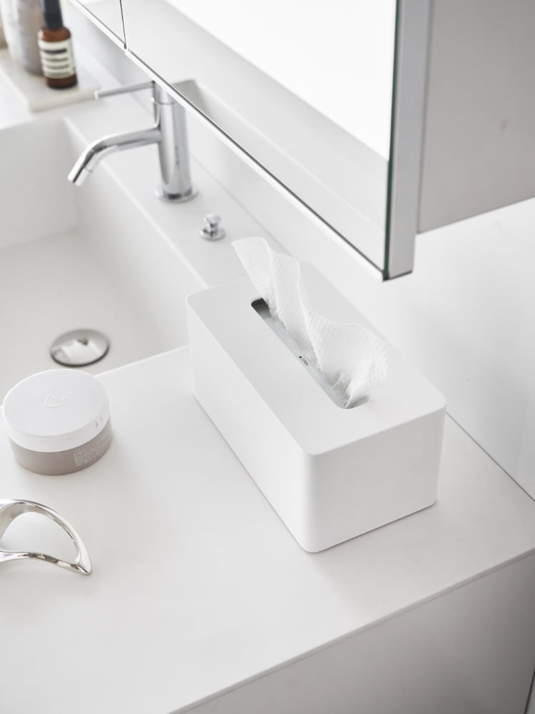 白い洗面台にグレーのバスルームキャビネットとタワークレンジングタオルケースが設置され、蛇口が配置されたバスルームの様子