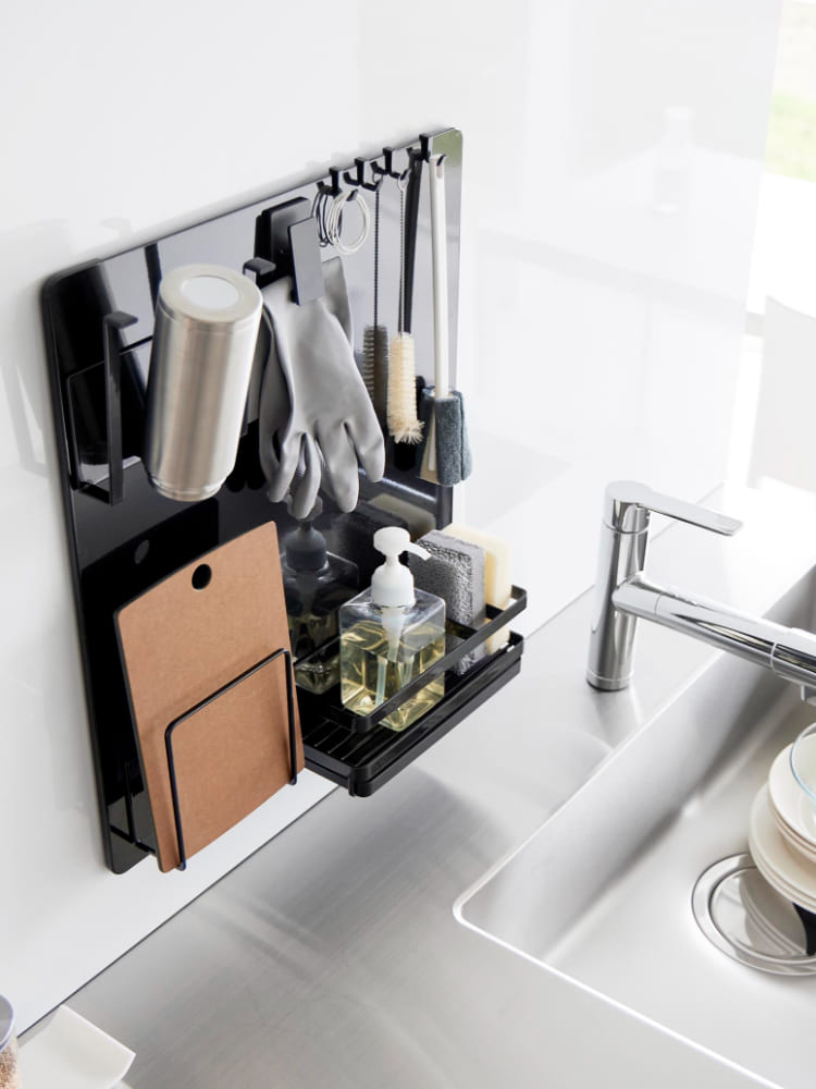 シンクと蛇口の隣に設置された銀色のタワーフィルムフックスチールパネル。キッチン用品やカトラリーが掛かっており、家庭用電化製品と観葉植物が周囲に配置されています