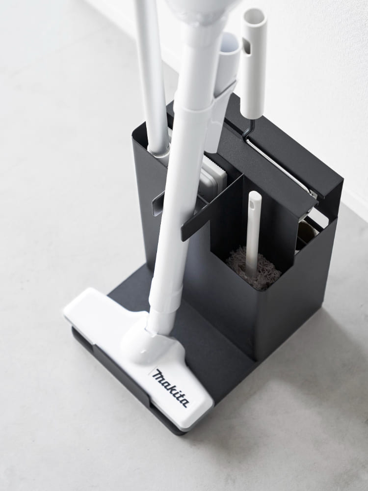 タワー型スティッククリーナー＆ツールオーガナイザーがスチール製台座上で家庭用掃除用品を整理して収納している様子