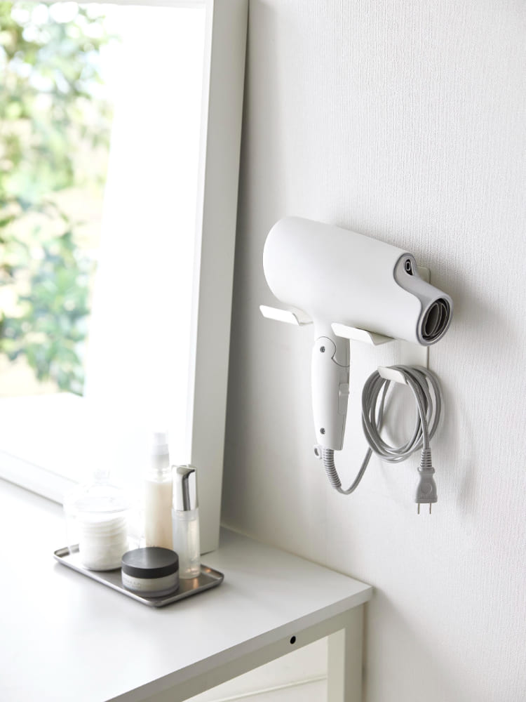 スチール製のタワーウォールドライヤーホルダーが石こうボードの壁にシルバー色で取り付けられている様子