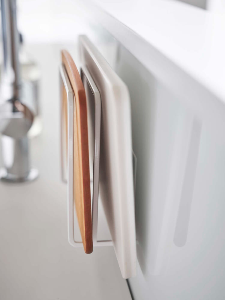 キッチンの壁に取り付けられたスチール製の木目調マグネットまな板スタンド。2枚のまな板を収納可能な塔型デザインです。