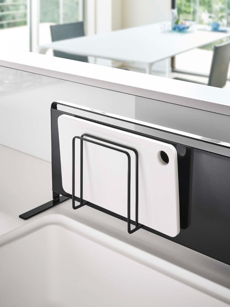 タワー型マグネットまな板スタンドがキッチンのスチール壁に取り付けられ、2枚のまな板を収納している様子