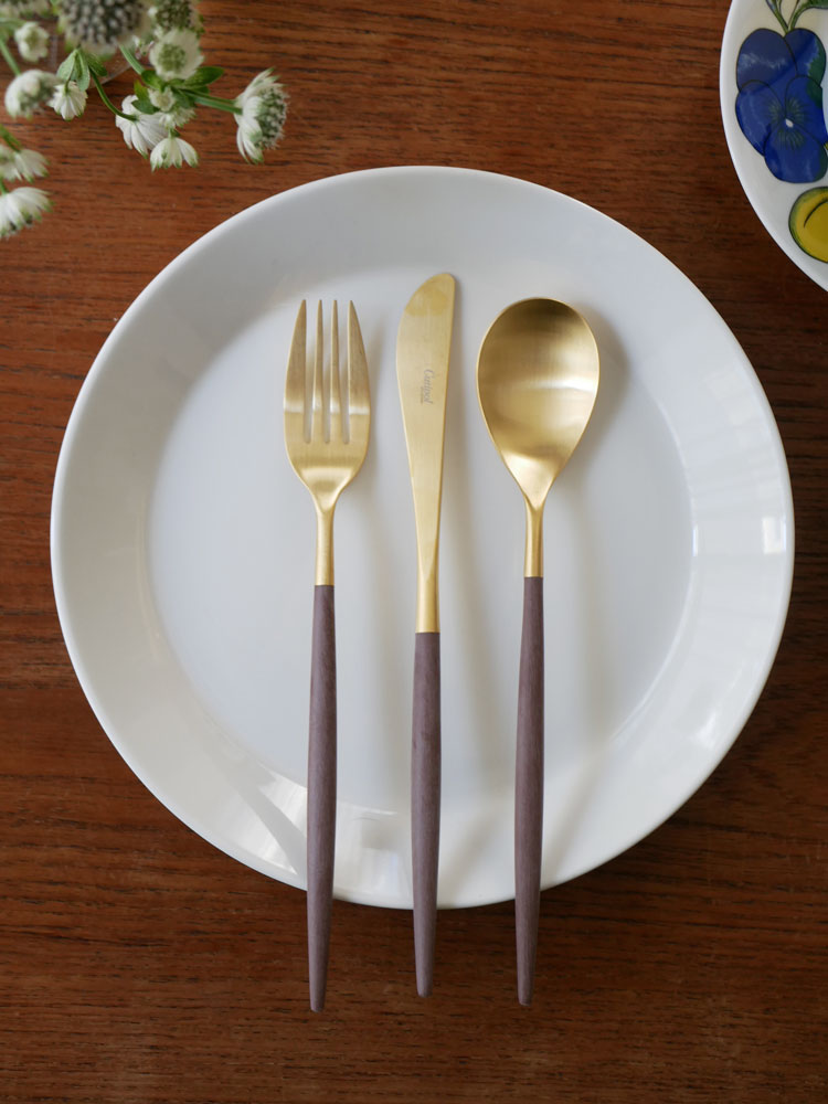 クチポールMIOシリーズのブラウンゴールド製ディナーフォーク、スプーン、ナイフが整然と並べられたテーブルセットの画像