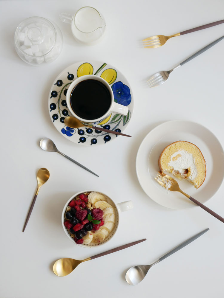 クチポールMIOシリーズのブラウンゴールドとグレーシルバーのディナーカトラリーセットが整然と並べられた食卓の写真