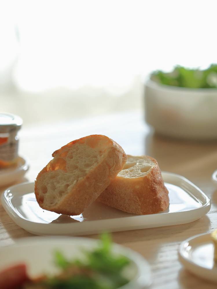 ホウケイ酸ガラス製の四角いプレート2点セットがテーブルに並び、白パンやファーストフードが盛り付けられている