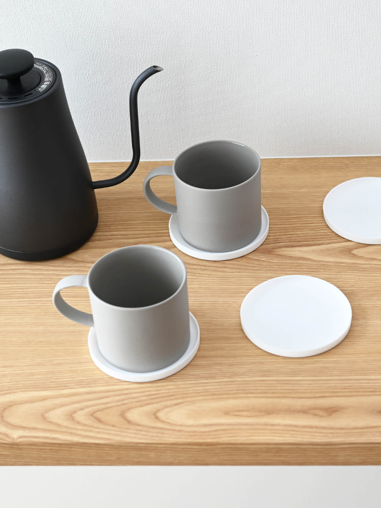 シリコーン製の立体タワーコースターの上にカップとティーポットが置かれているテーブルの様子