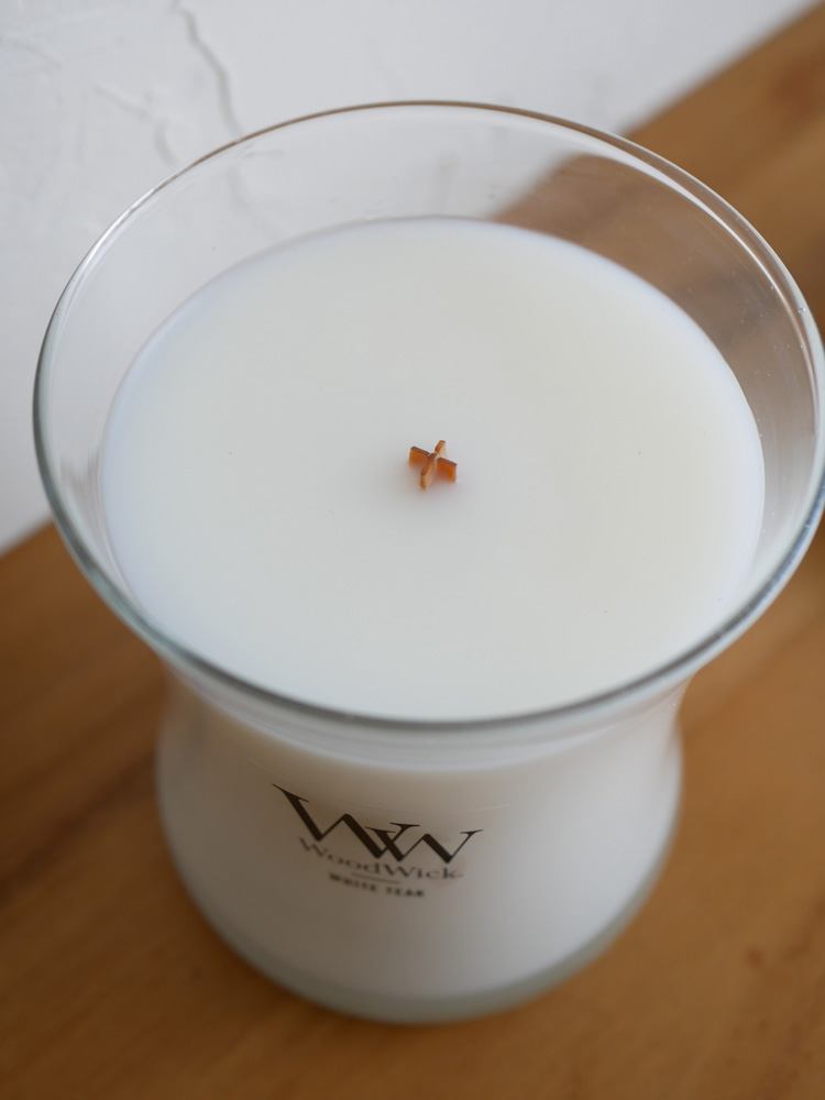 木製芯の炎を灯したガラス製キャンドルとホルダー