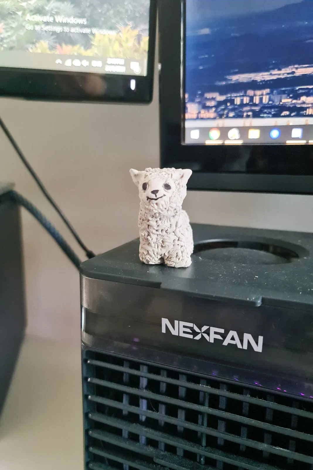 A small clay alpaca figurine sitting atop a NEXFAN air cooler