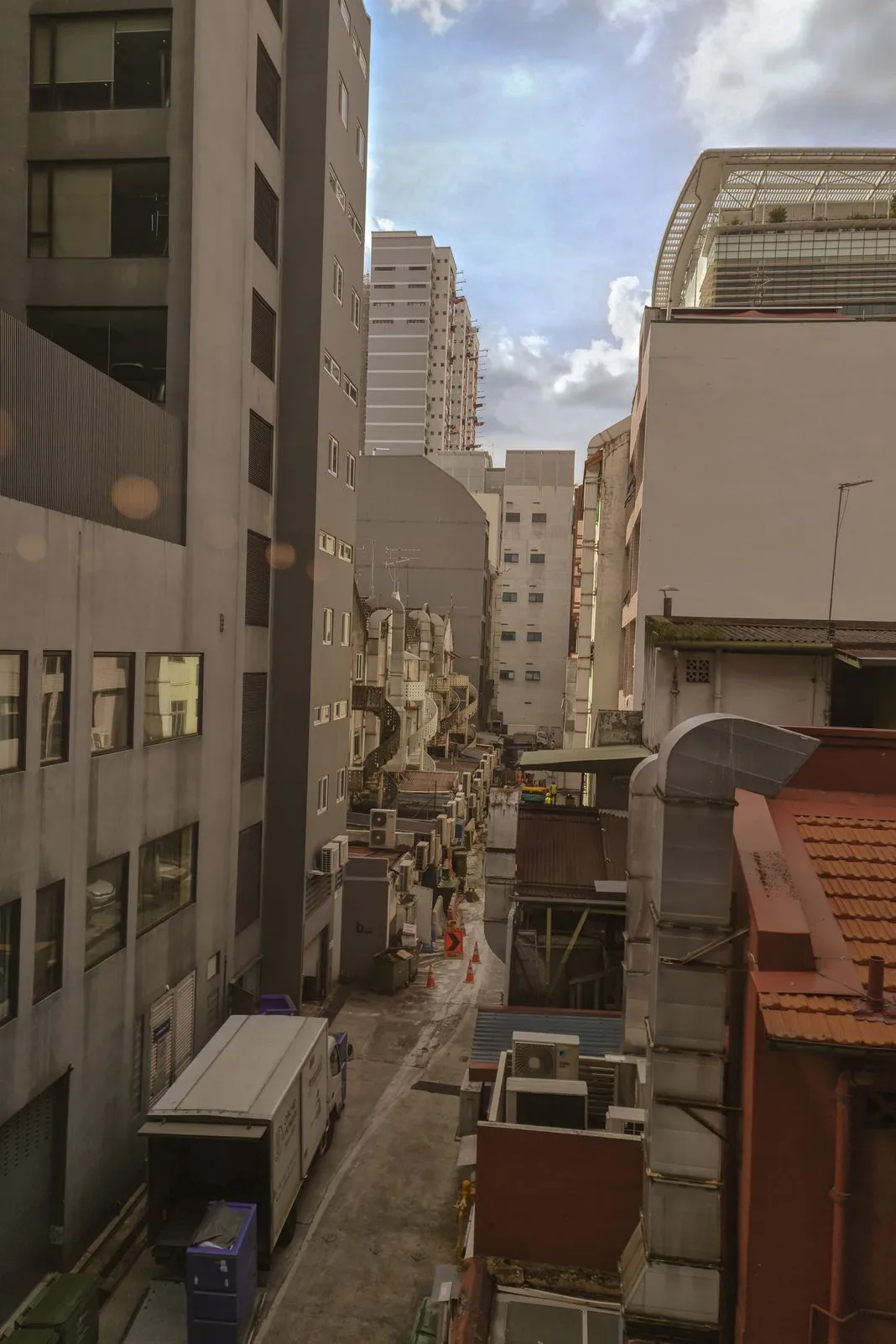 A narrow city alley between buildings with a spiral fire escape staircase