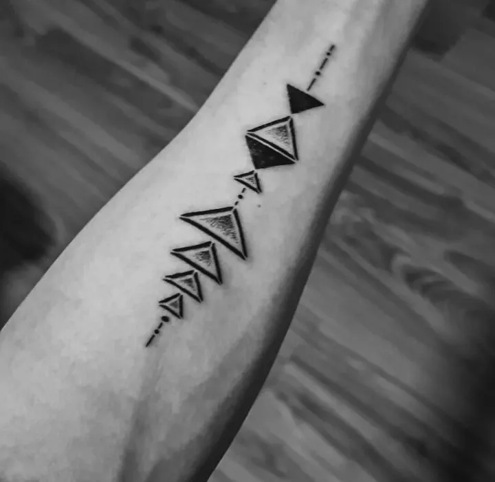 A geometric triangle line tattoo running along a forearm
