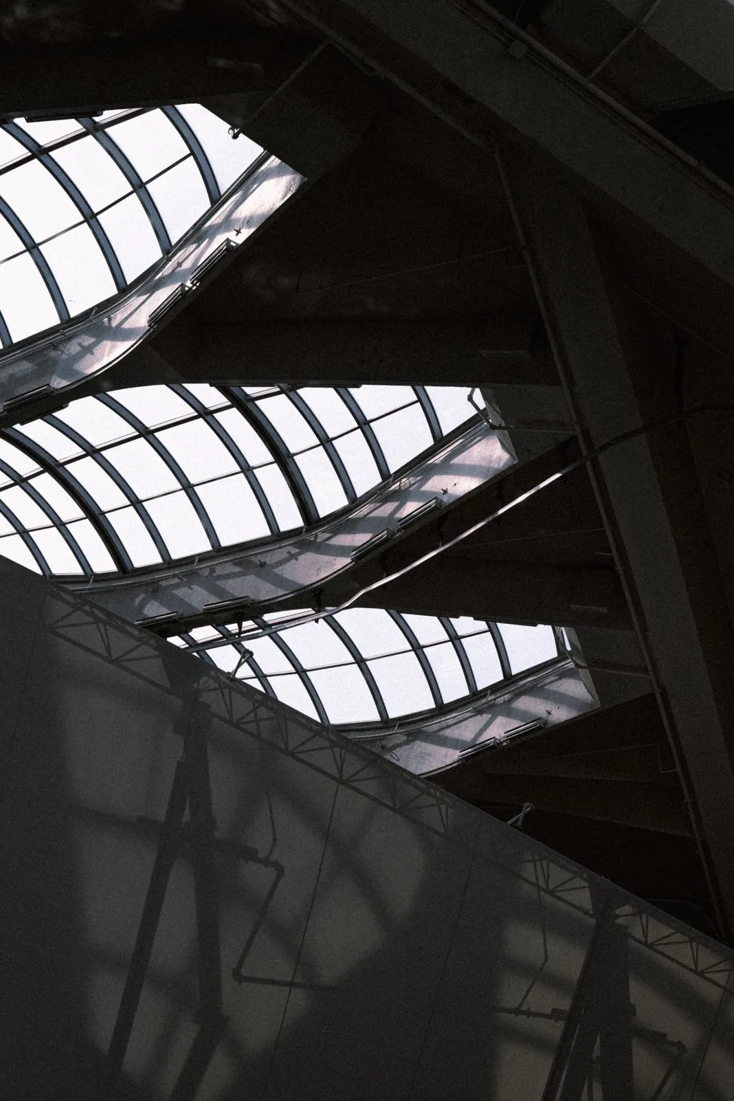 Looking up at overlapping skylights and steel framing inside a building