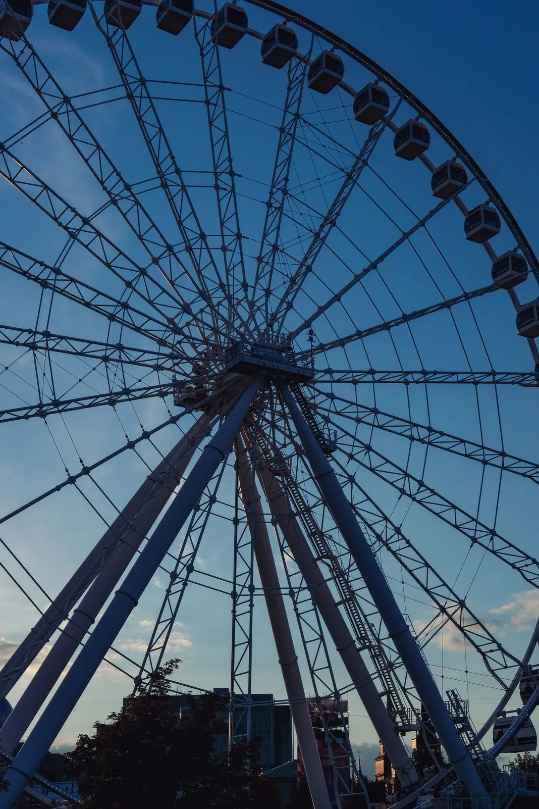 Silhouette of a large Ferris wheel against a darkening blue sky