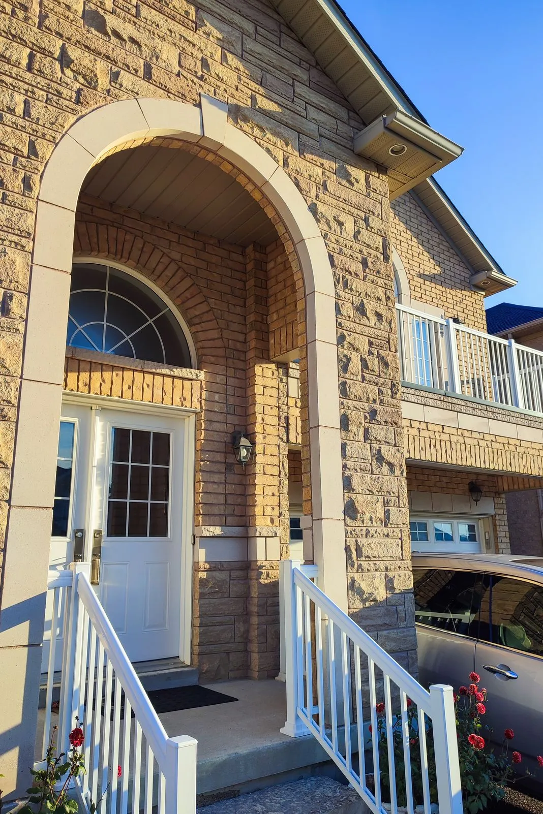 Front entrance of a stone-clad house with an arched doorway and staircase