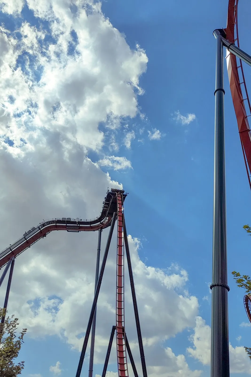 Roller coaster track rising steeply against a bright cloudy sky