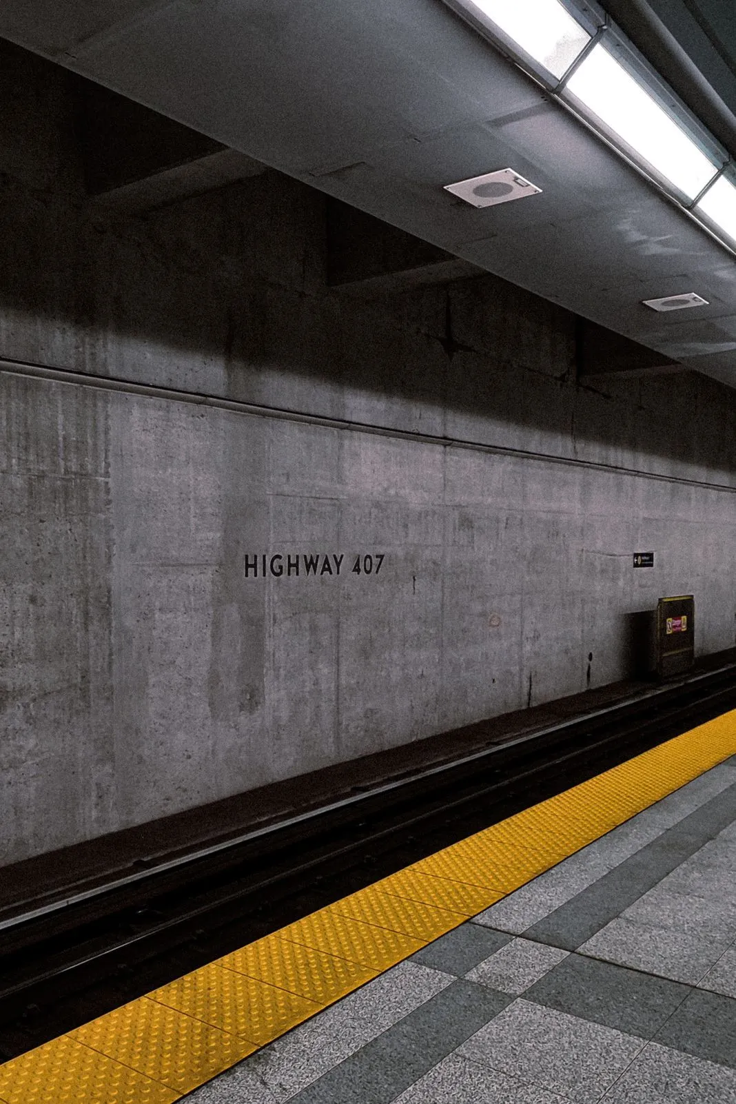 Subway platform with a "Highway 407" station sign along the yellow safety strip