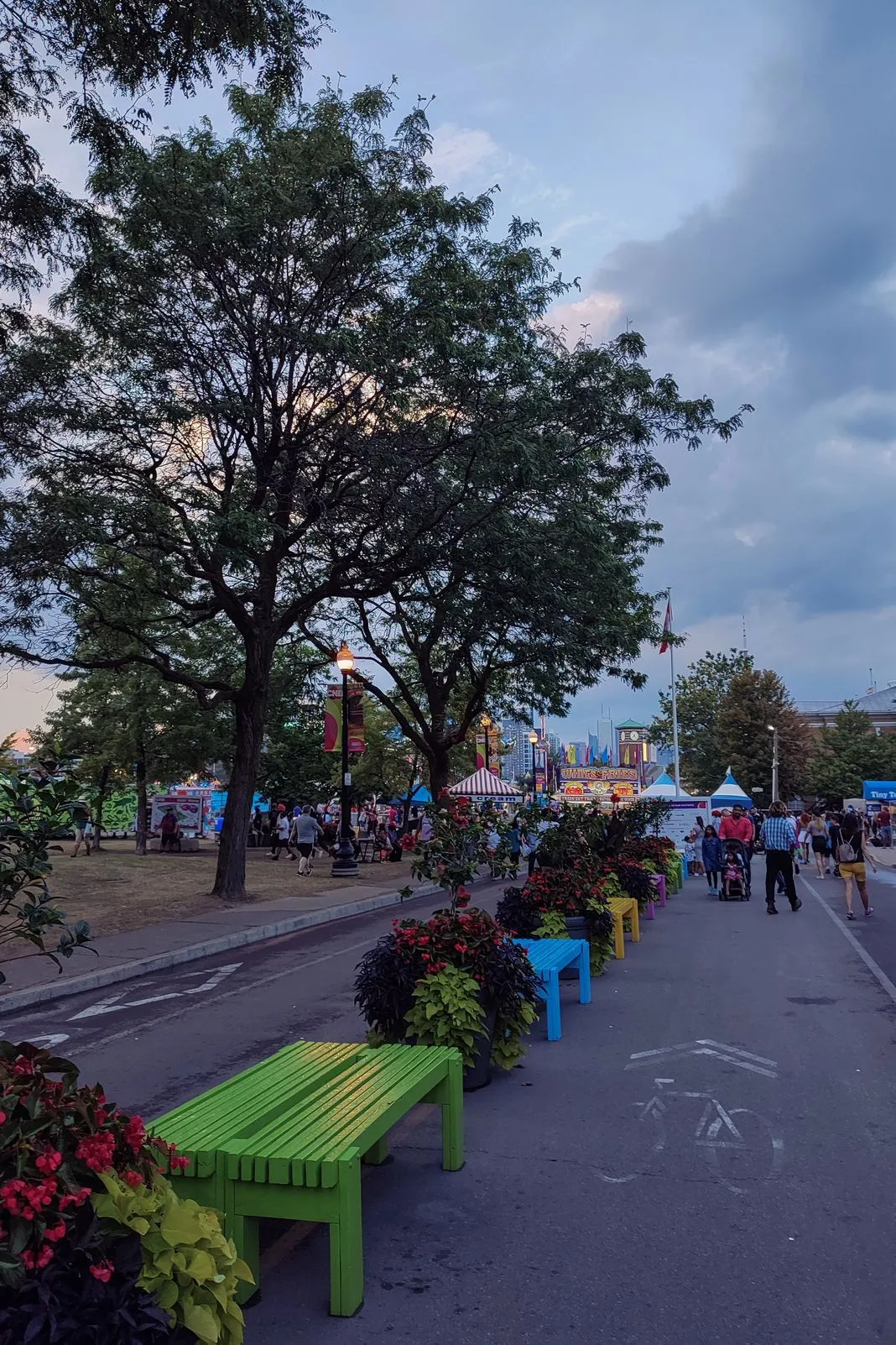 Colorful benches lining a path through a fairground at dusk