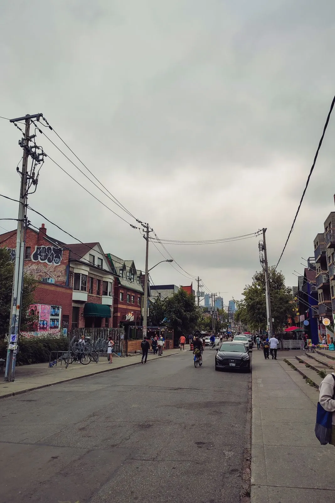 Quiet residential street with graffiti-tagged buildings and a distant skyline
