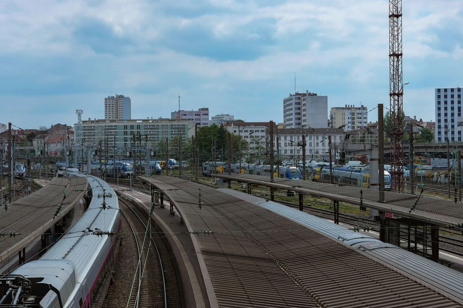 Multiple rail platforms and tracks at a train station, with the city skyline behind