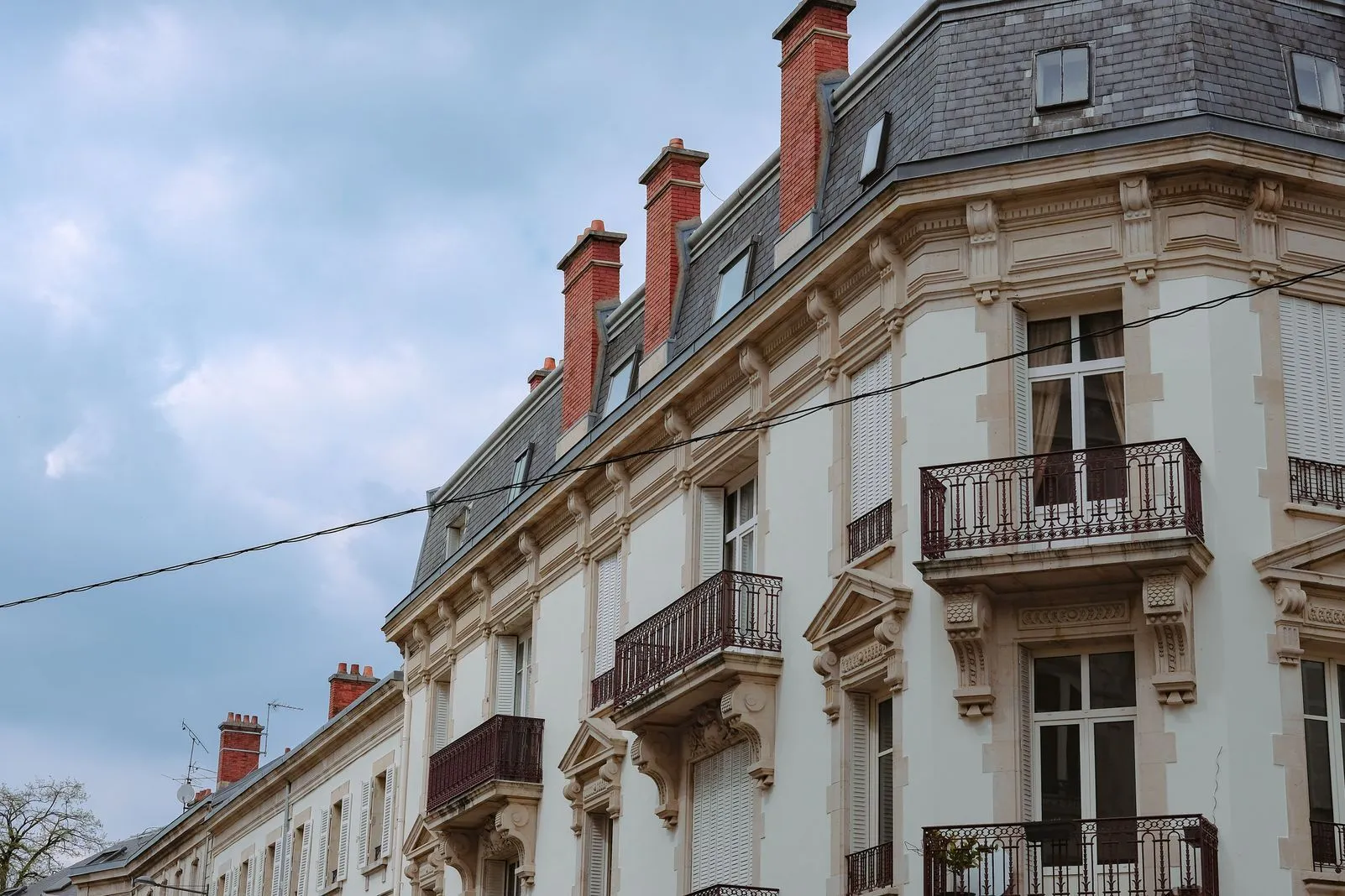 Cream-colored Haussmann-style facade with red brick chimneys and ornate iron balconies