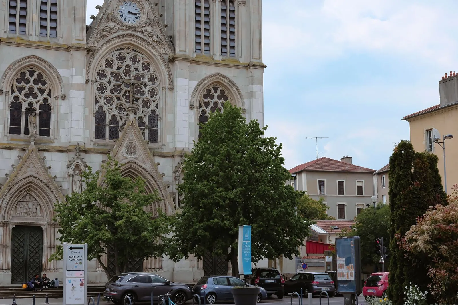 Gothic cathedral facade with a rose window, statue, and clock tower
