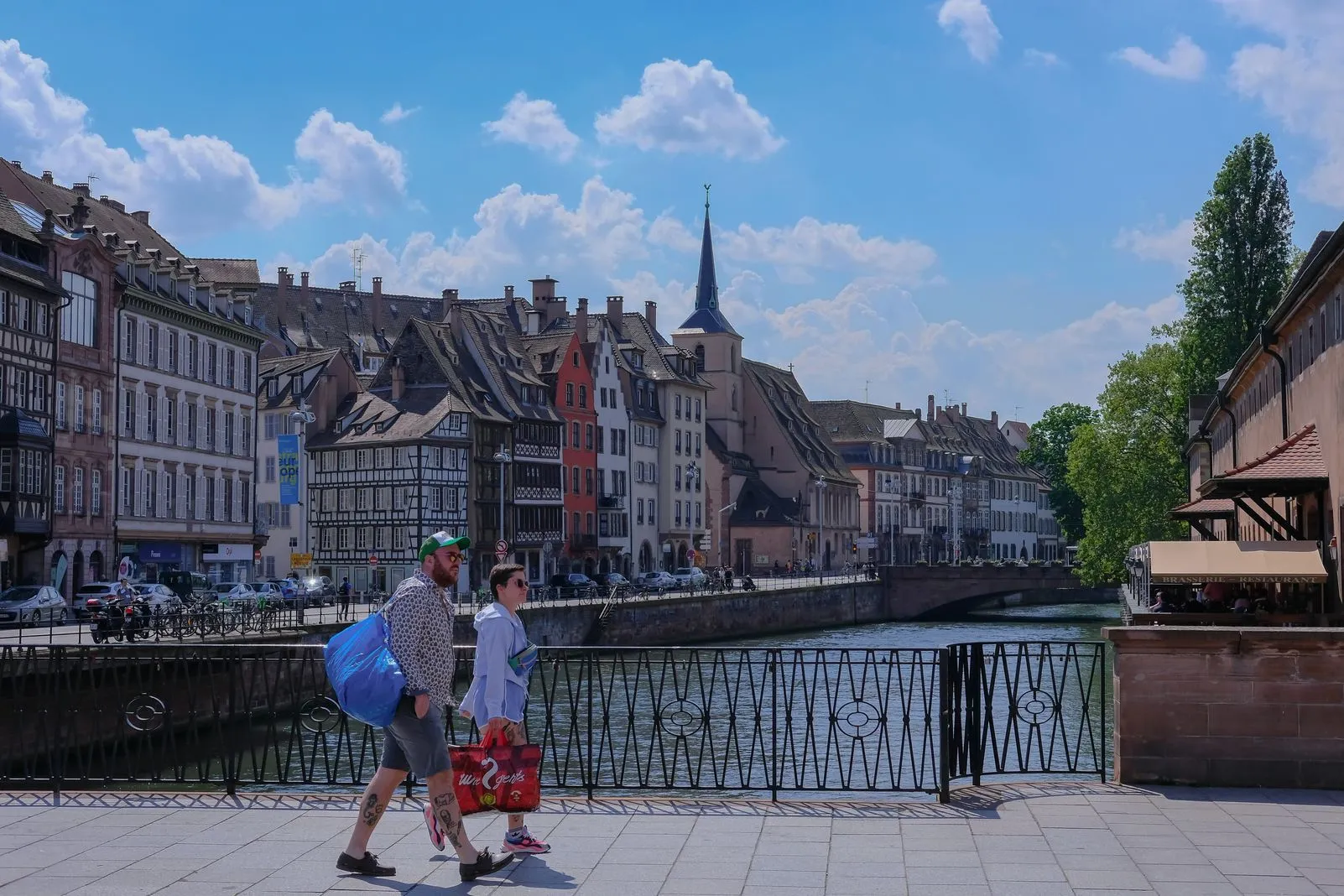 Couple walking along a canal lined with half-timbered houses and a church spire