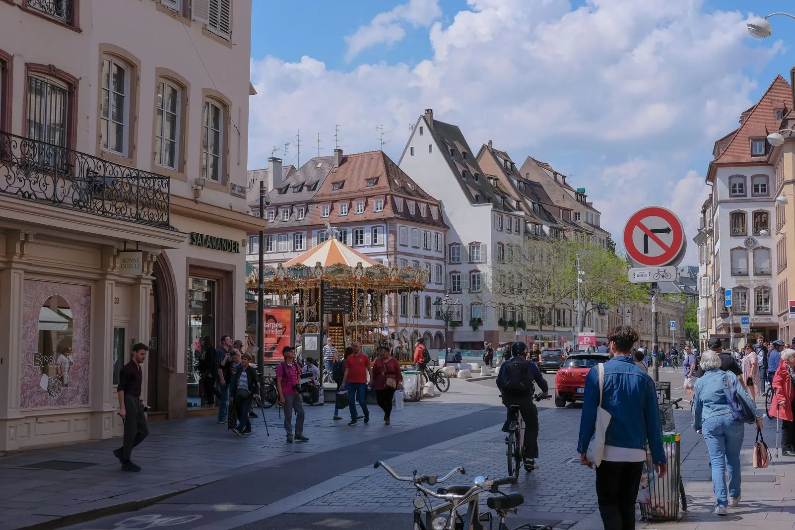 A carousel and gabled half-timbered buildings on a busy pedestrian street