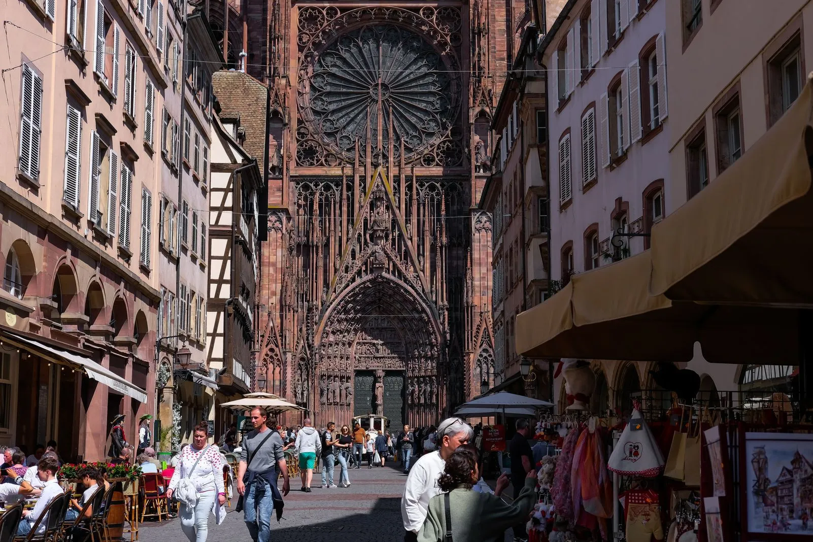 Strasbourg Cathedral's rose window towering above a narrow street with market stalls