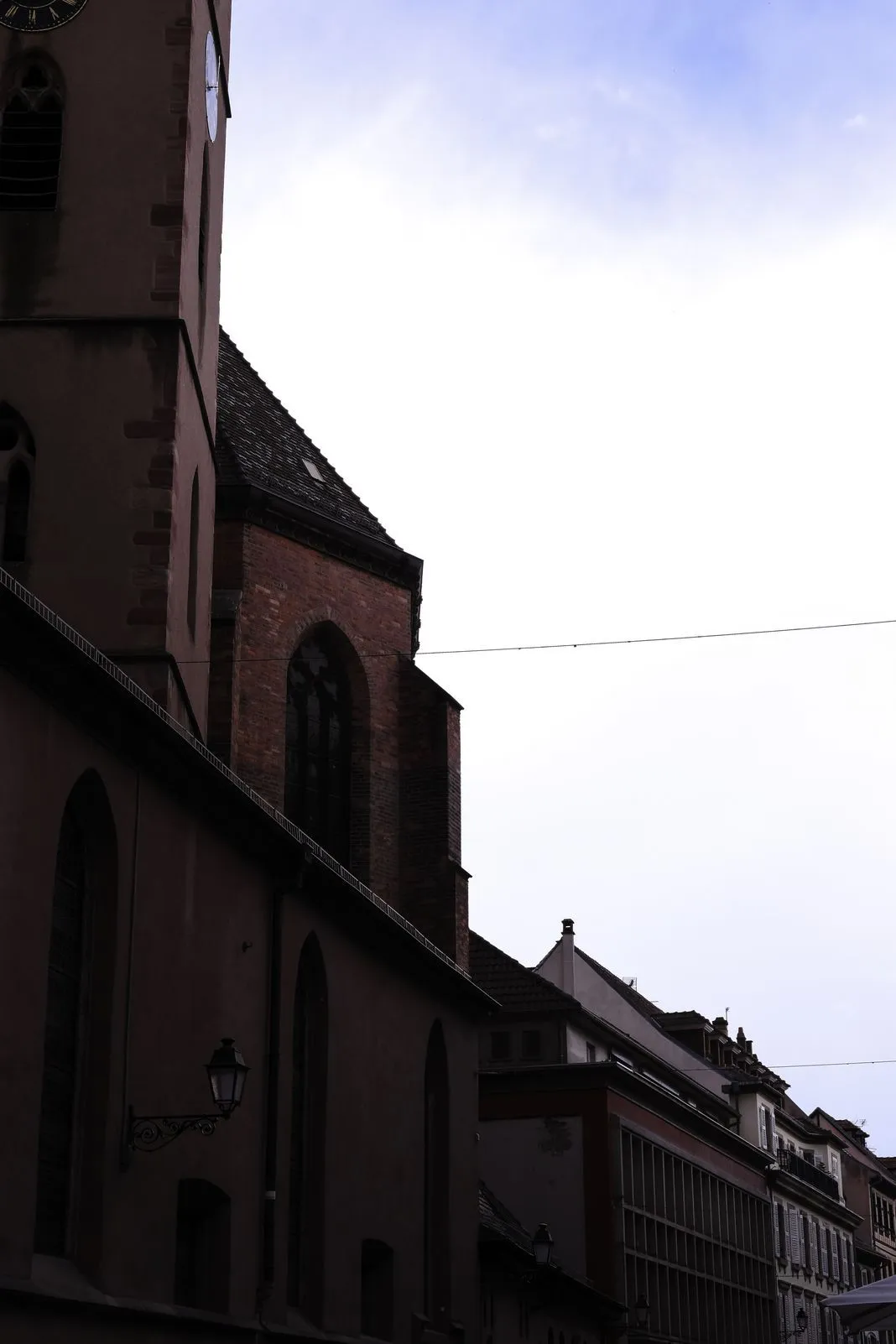 Looking up at a church bell tower silhouetted against an overcast sky
