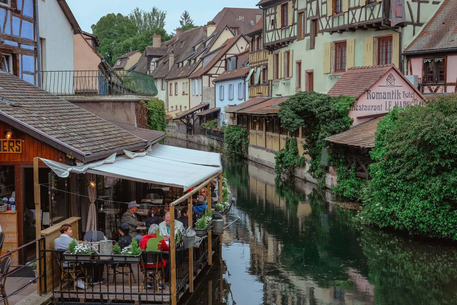 Diners on a canal-side terrace among half-timbered houses in Colmar's Little Venice