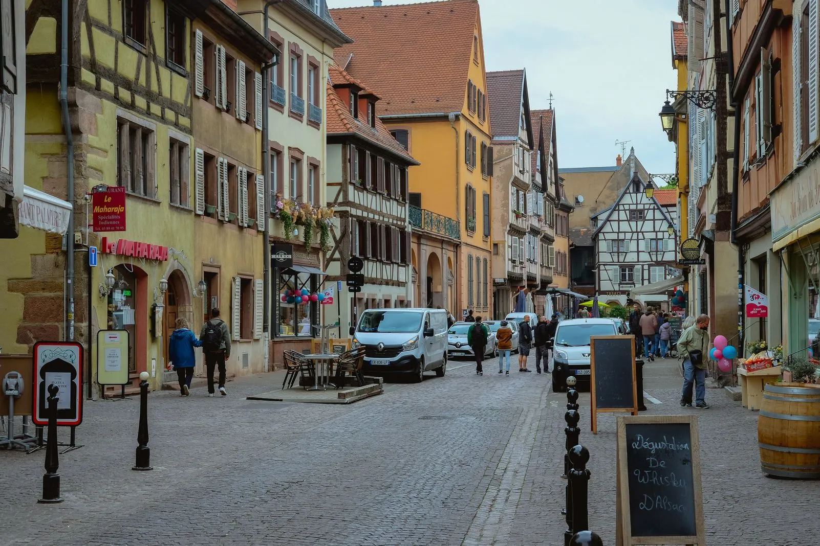 Cobbled street lined with colorful half-timbered buildings and outdoor cafe tables