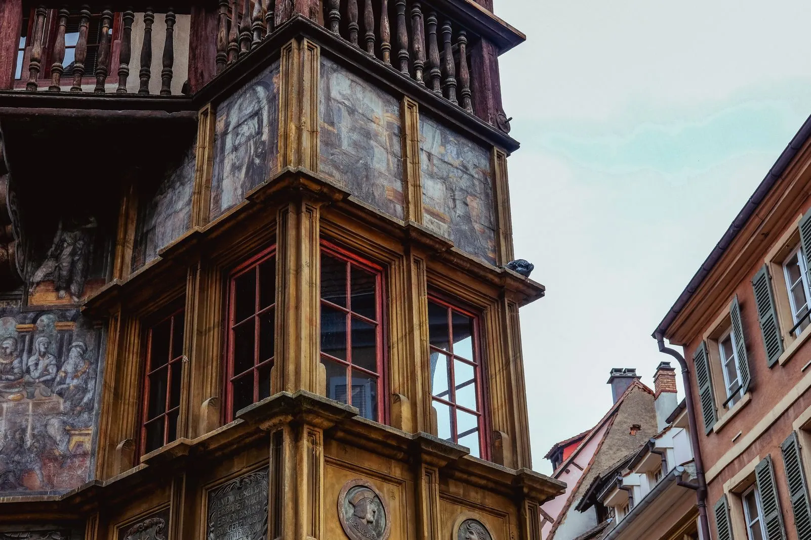 Ornate painted facade of a historic timber-framed building with red window frames