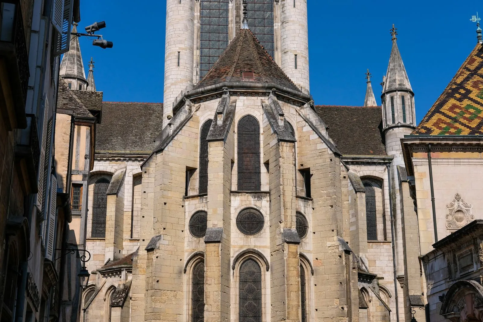 Gothic church facade with pointed spires and a colorful glazed-tile roof nearby